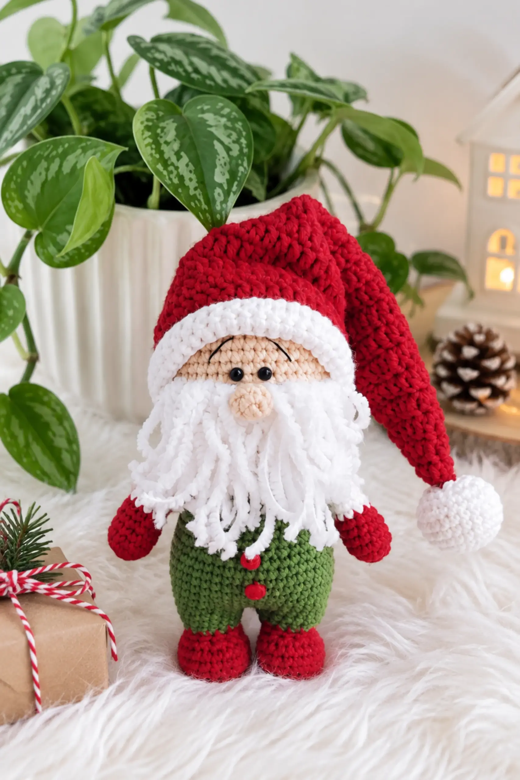 Finished Christmas gnome amigurumi with a long red hat, white beard, and green overalls sitting on a fur rug