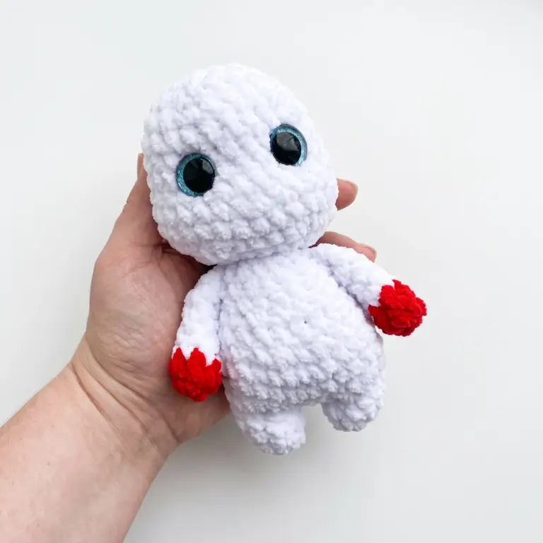 Hands joining the crocheted body and legs of the ushanka snowman amigurumi before stuffing