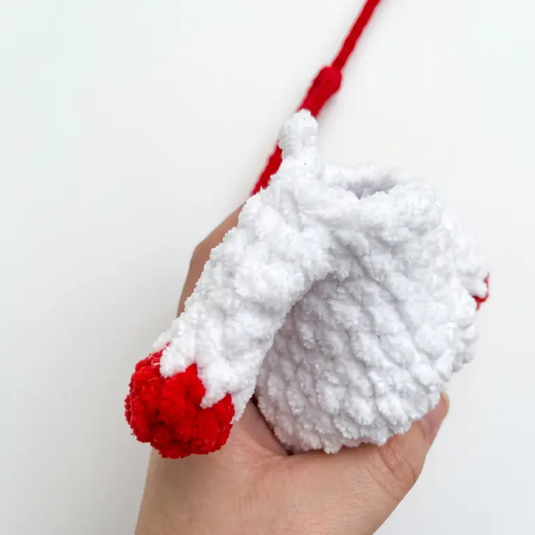 Attaching a crocheted mitten arm to the ushanka snowman amigurumi's body