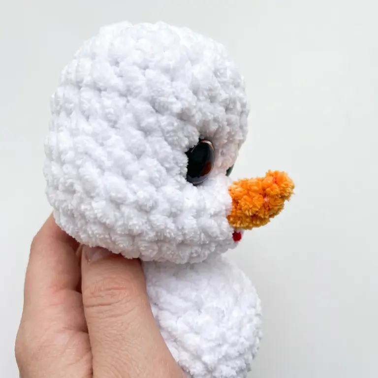 Side profile of the snowman amigurumi head showing the attached carrot nose